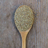 Light brown and green celery seed on a rustic wooden spoon.