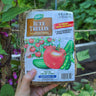 Gardener holding a package of natural material trellis against a healthy garden background.