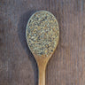 Rich yellow and brown lemon pepper on a rustic wooden spoon.
