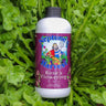 Neptune's Harvest Rose & Flowering fertilizer bottle on a bed of healthy green plants