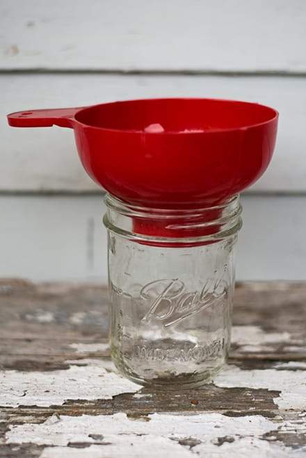 Bright red canning funnel set up in a mason jar