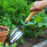 Hand holding a deep garden scoop tool in a raised bed garden.